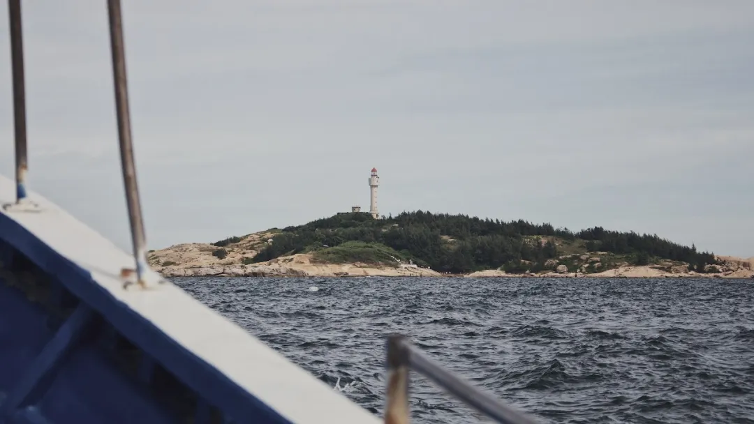 Lighthouse Island in Red Bay seen from a speedboat, the white lighthouse rising from a green slope.