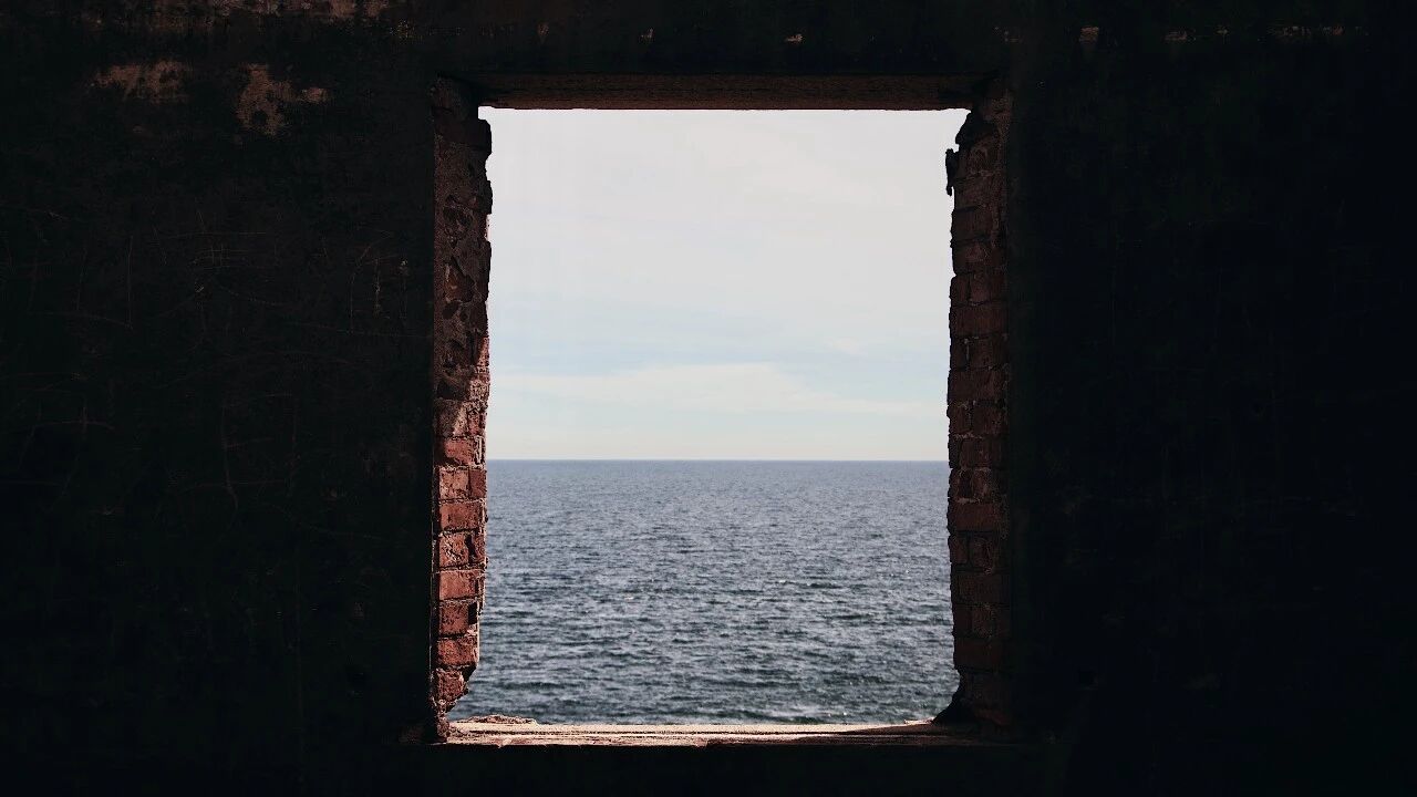 The South China Sea framed by the empty window of an abandoned brick building on the Shanwei coast.