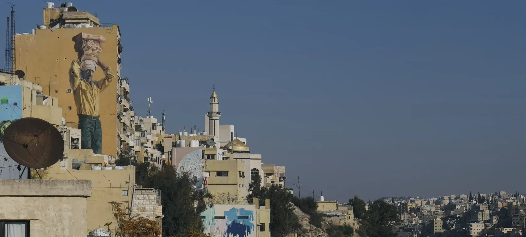 Amman hillside buildings under hard blue sky.