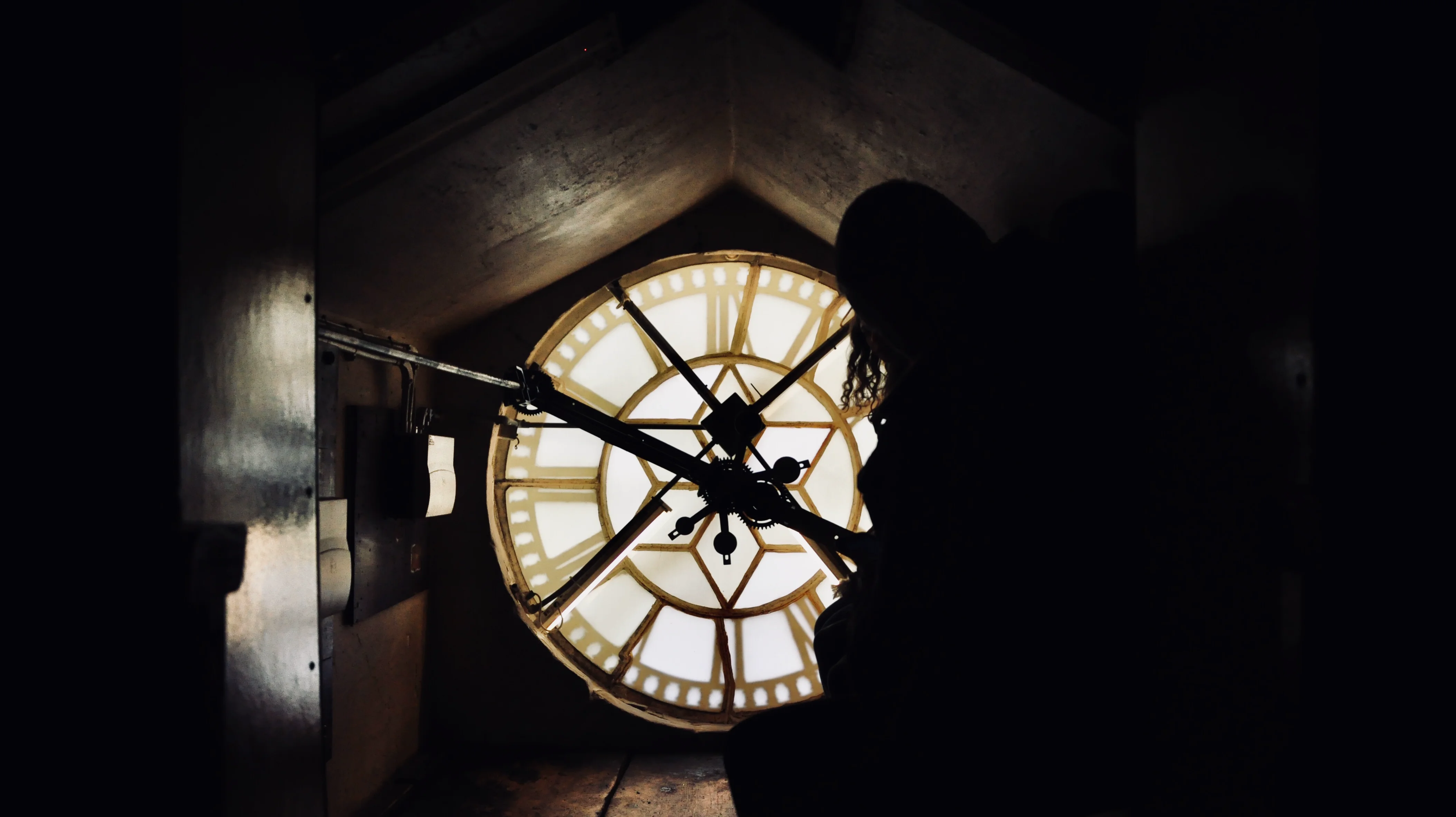 A silhouetted figure inside a clock tower mechanism in Bath.