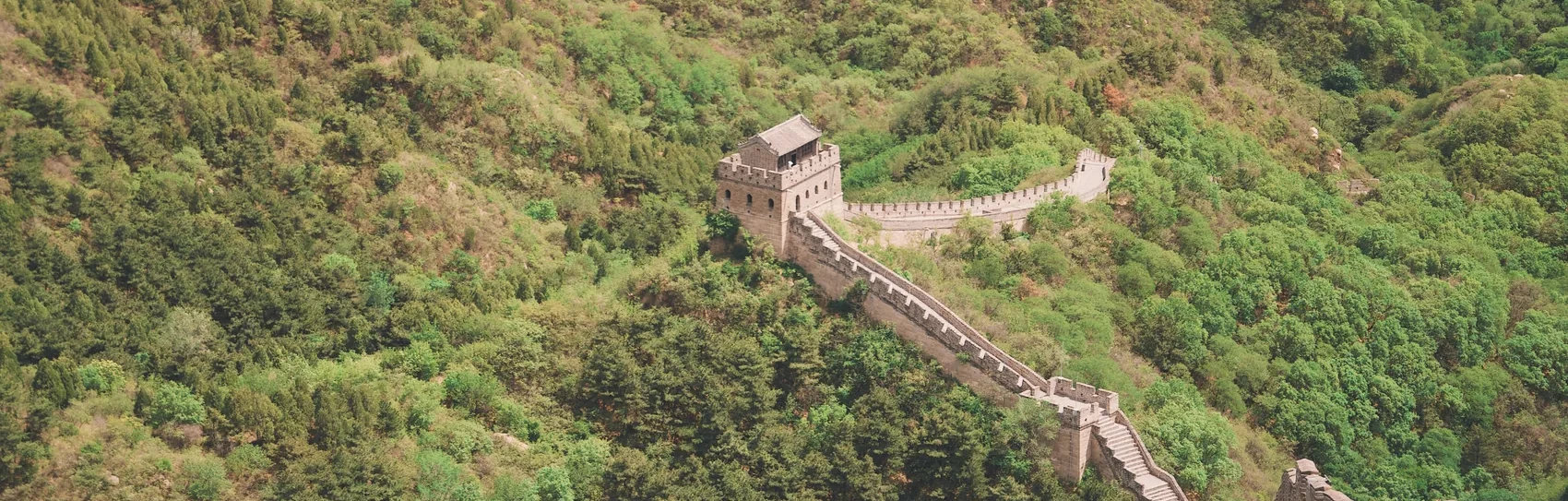 The Great Wall crossing green Beijing mountains.