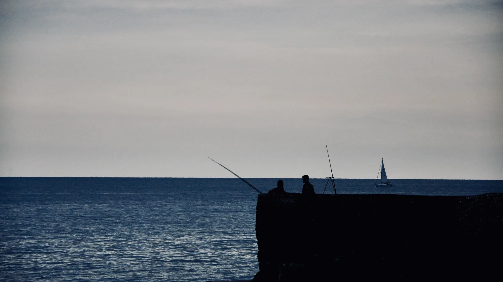 A dark Brighton pier edge against a flat sea horizon.
