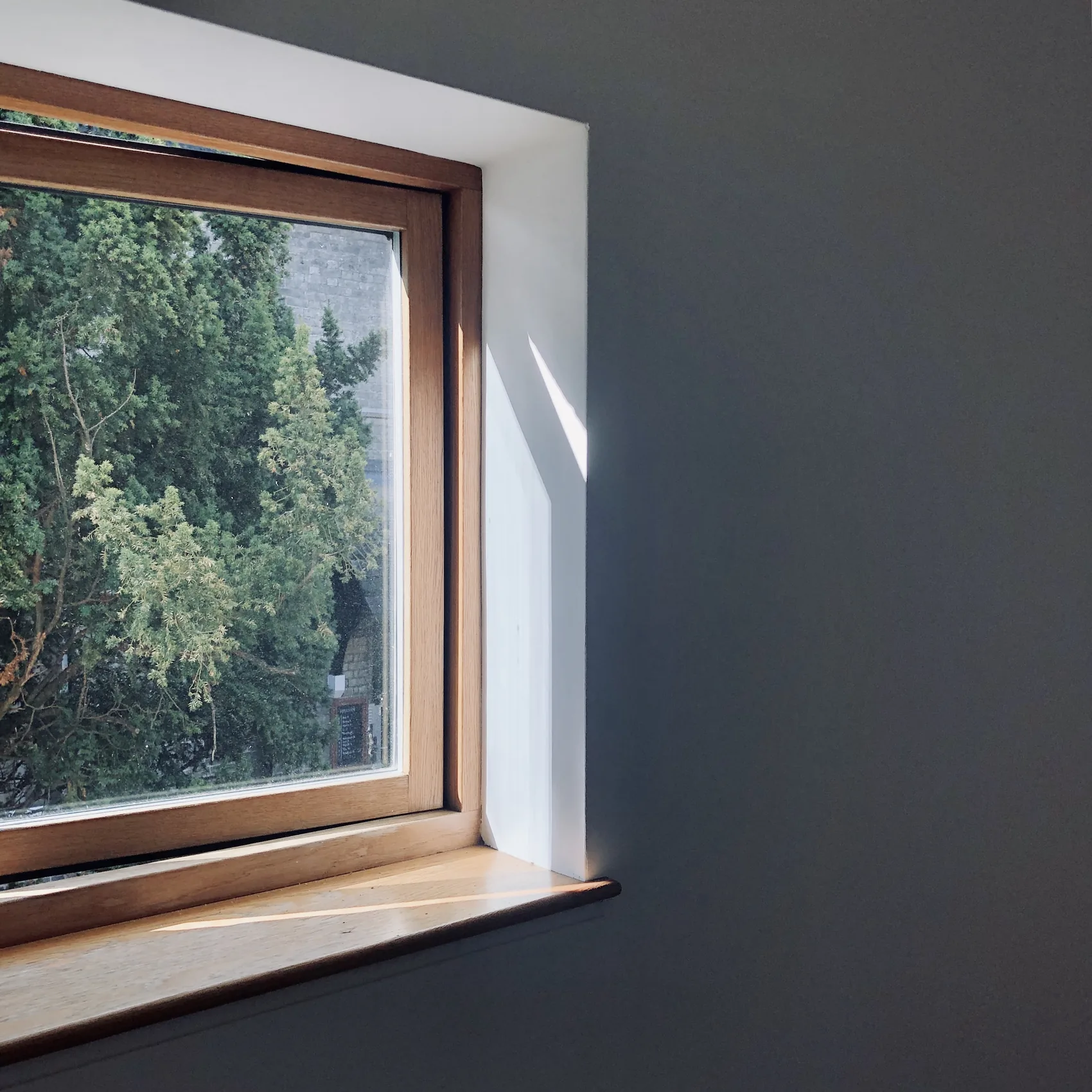 A square Cambridge window with a narrow shaft of light.