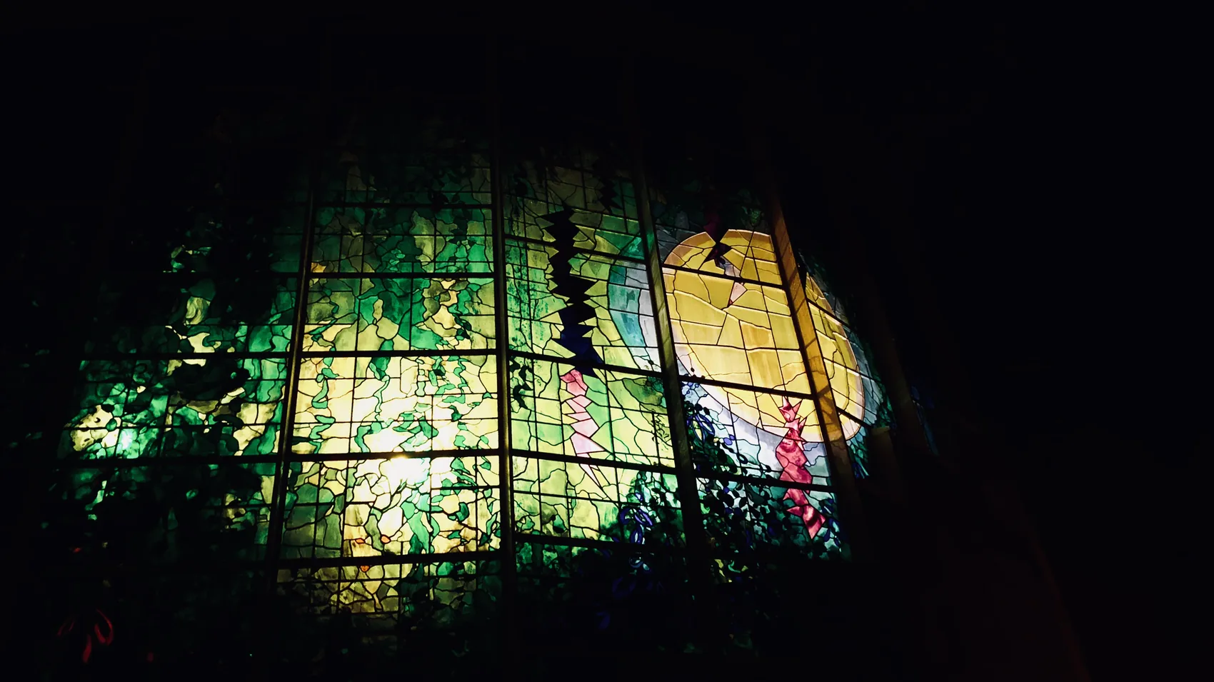 A stained glass Cambridge window glowing in green and gold.