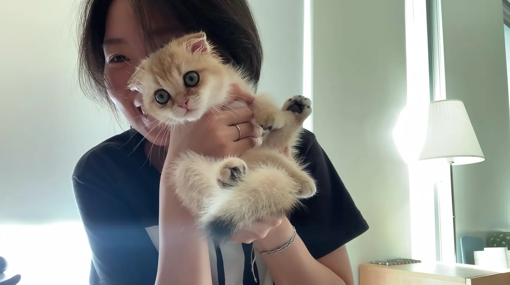 A smiling person holding a ginger kitten.