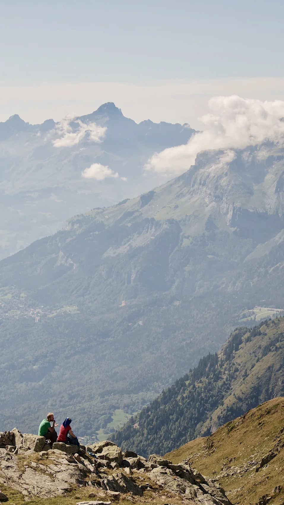 Two people resting on a Chamonix ridge above haze.