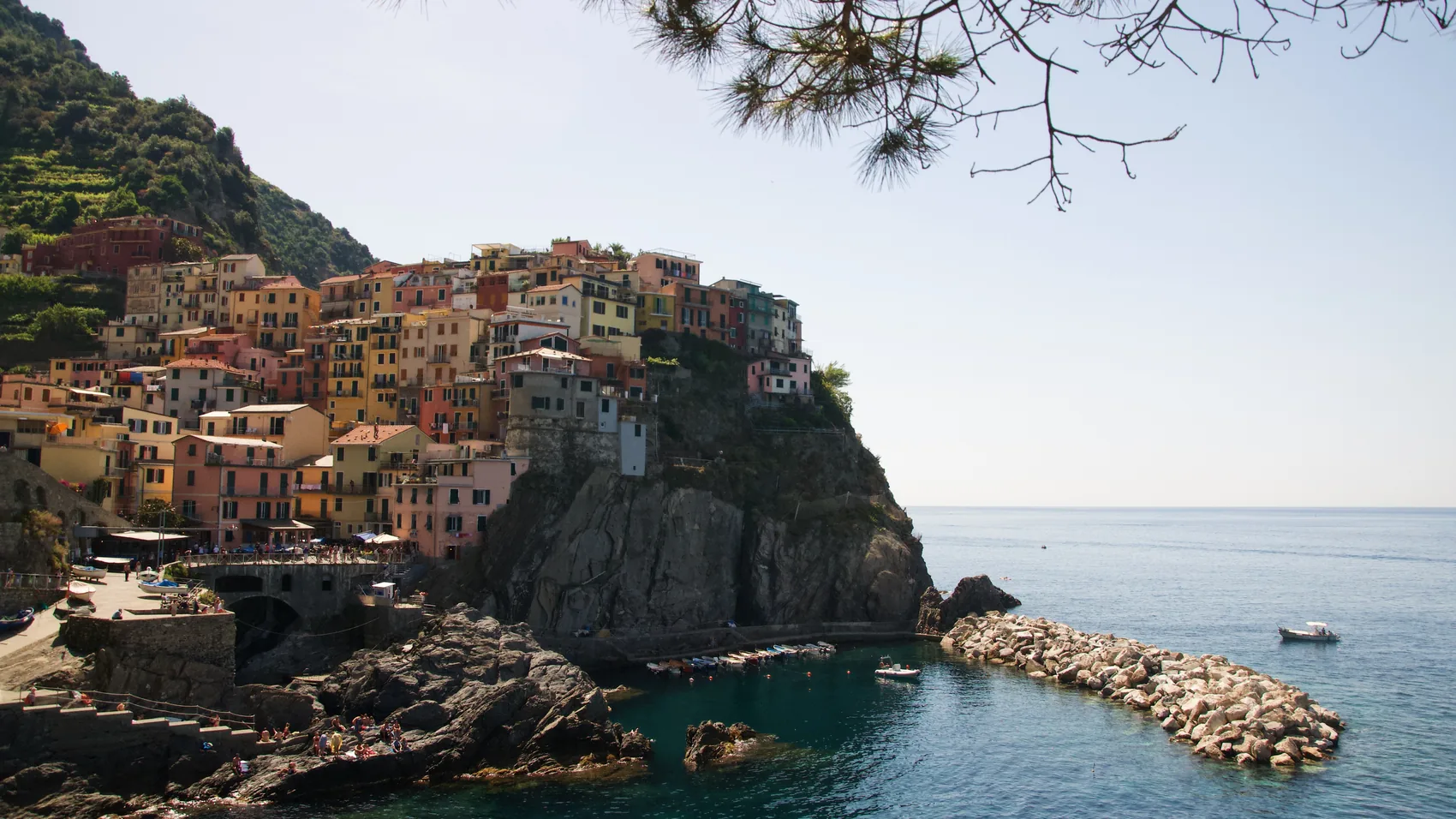 A Cinque Terre harbour and cliff town in bright sun.