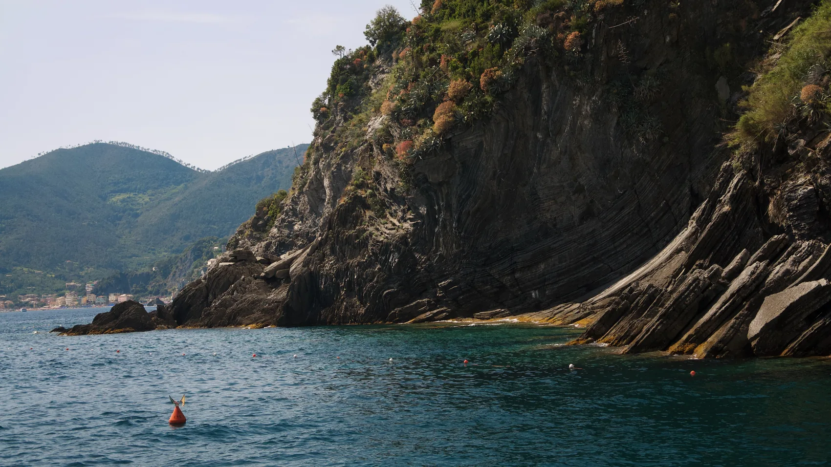 A lone swimmer below dark Cinque Terre rock.