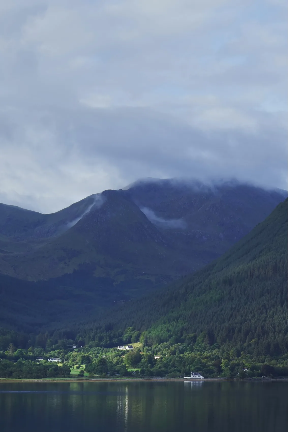 A blue Highland loch under clouded mountains.