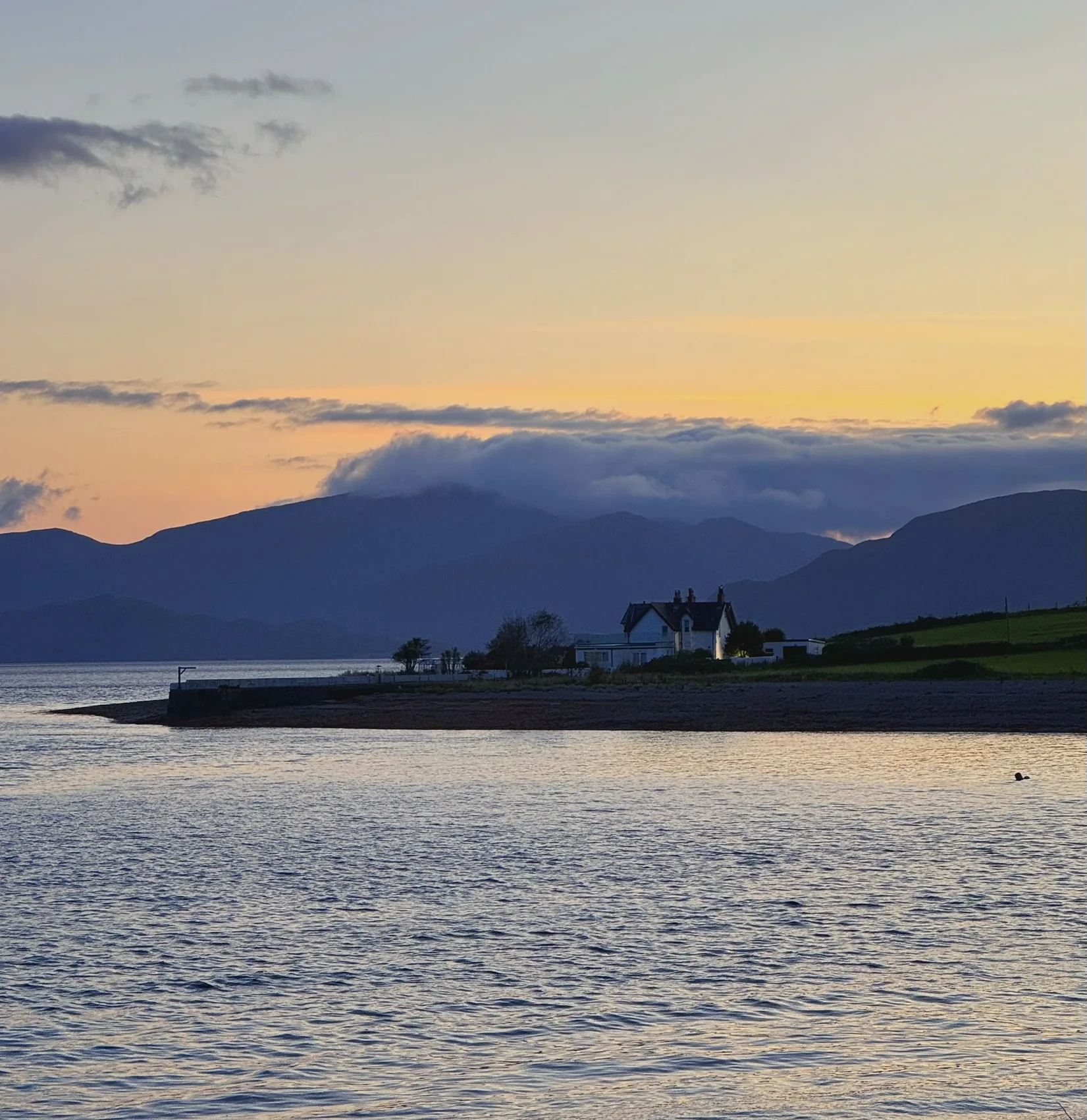 A Highland loch at sunset with mountains in silhouette.
