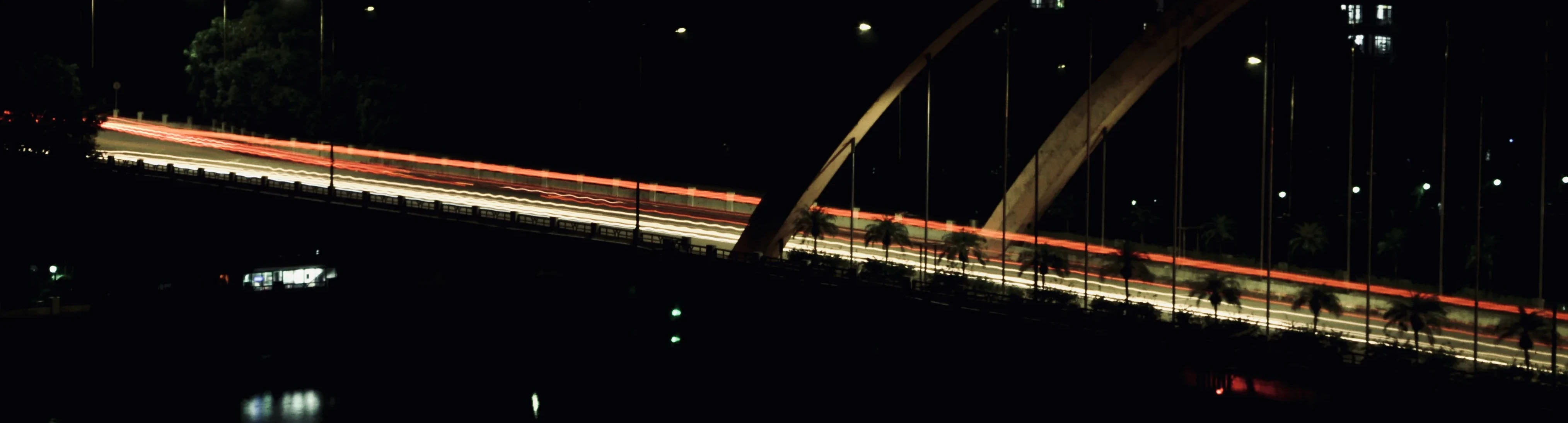 A Guangzhou bridge at night with long-exposure light trails over the river.