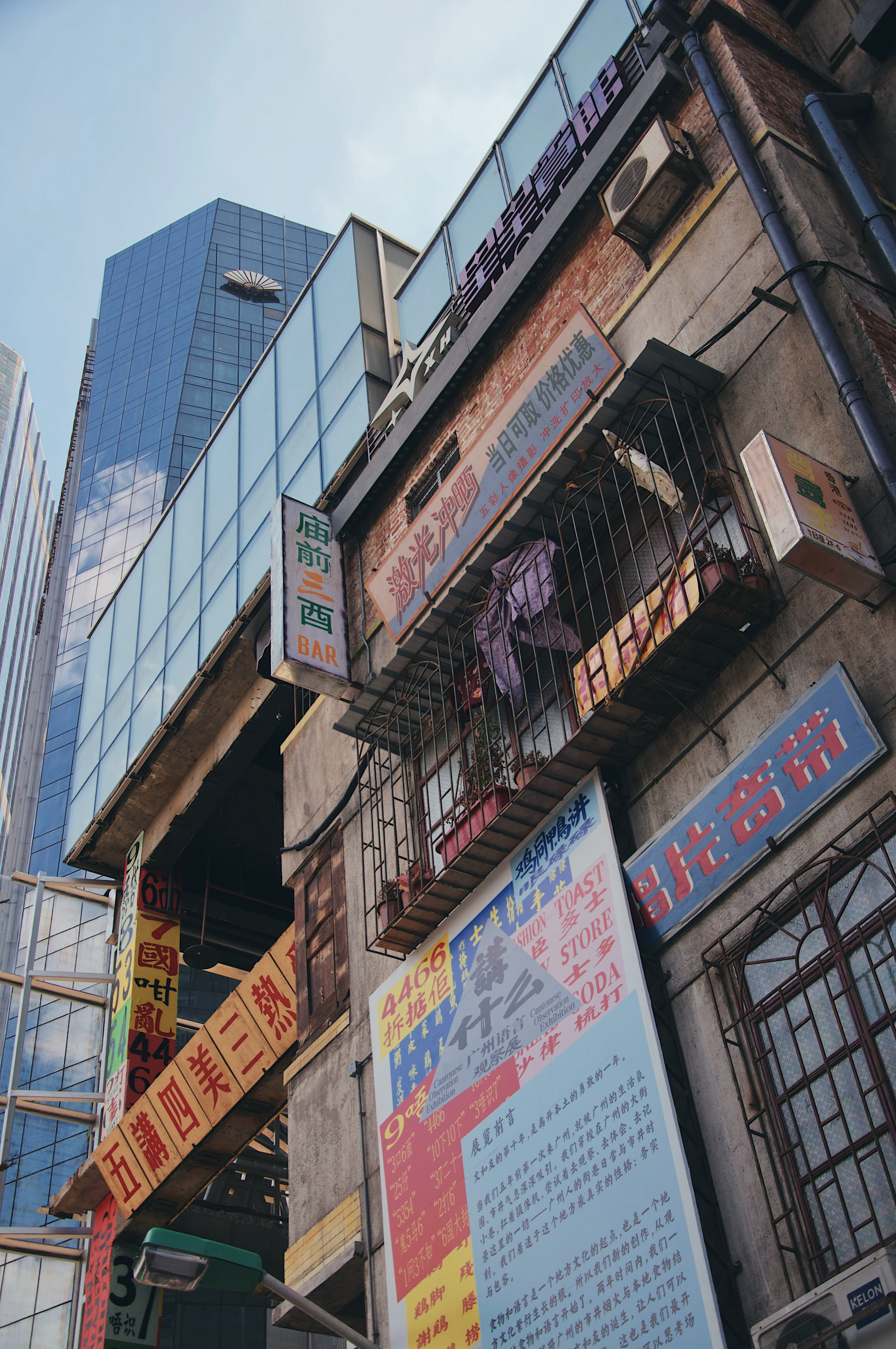 Dense Chinese signage on an old Guangzhou building with a glass tower behind.