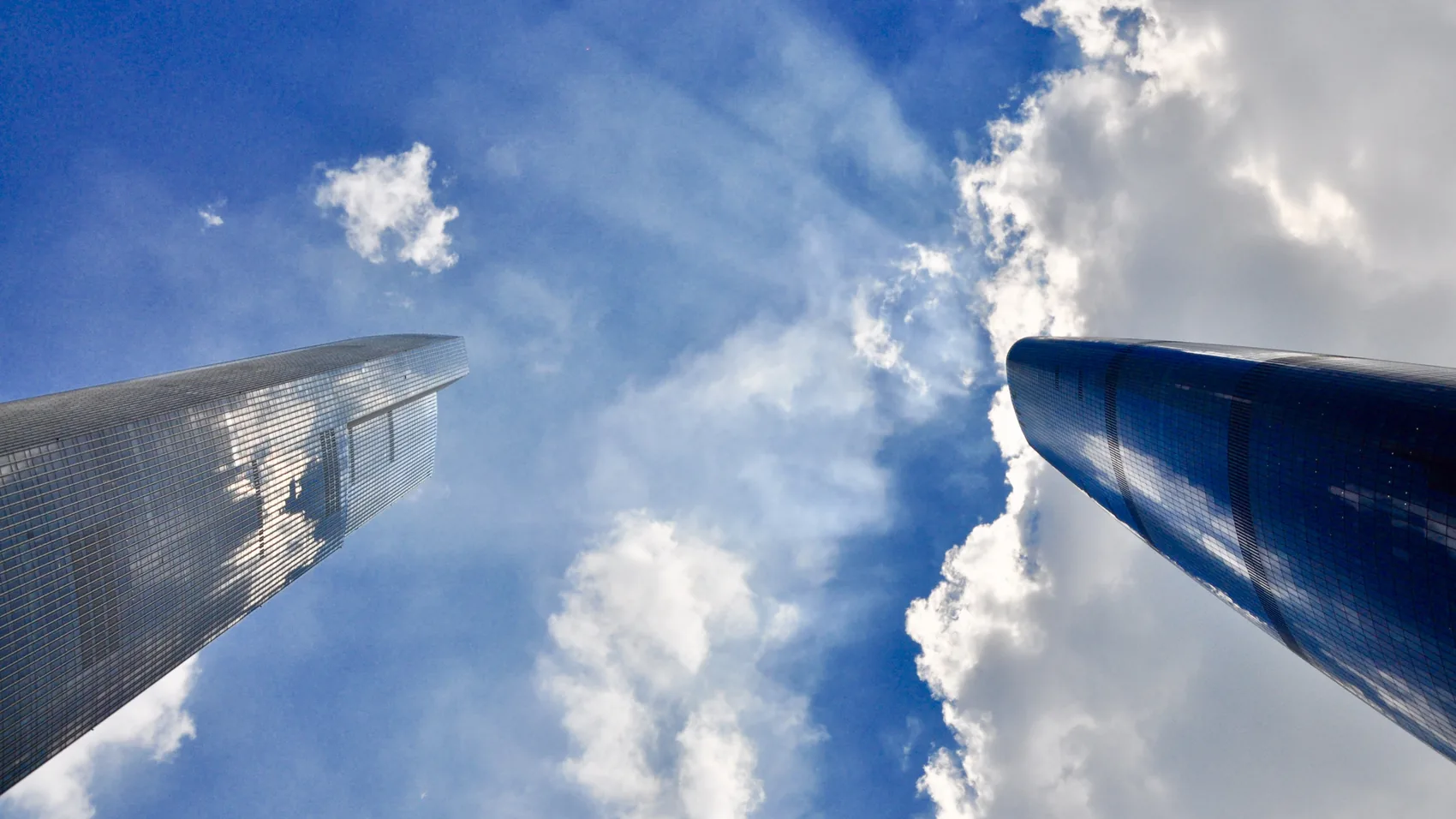 Two Guangzhou towers rising into blue sky and cloud.