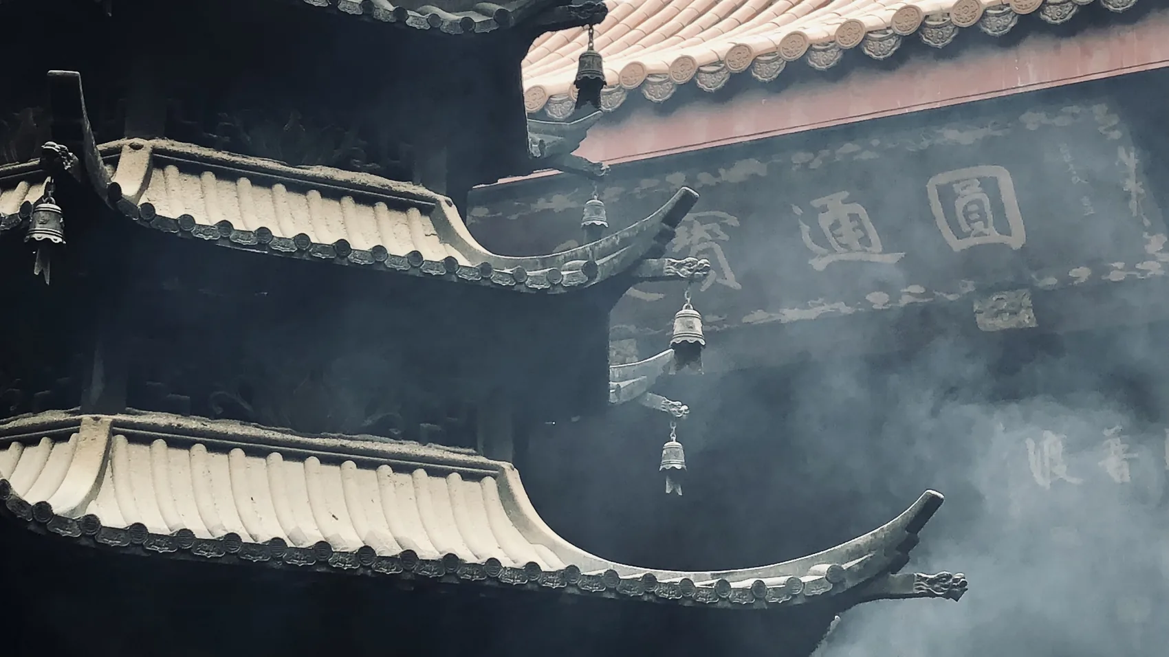 Smoke rising around Hangzhou temple roof tiles.