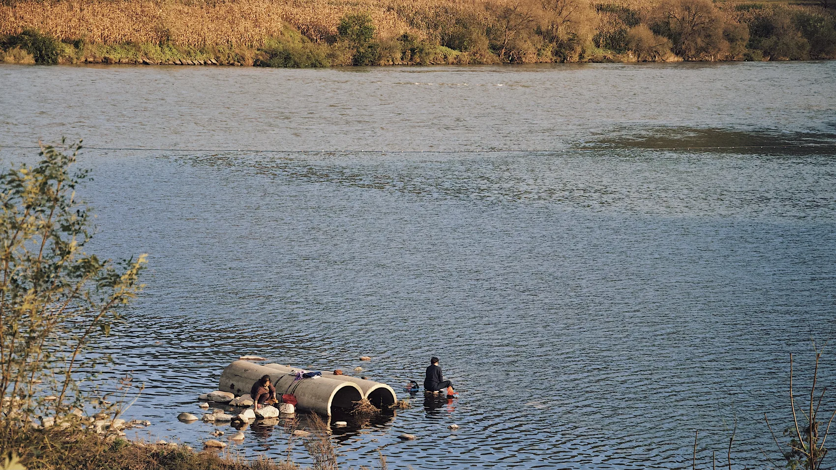 A person near pipes at the edge of a Jilin river.