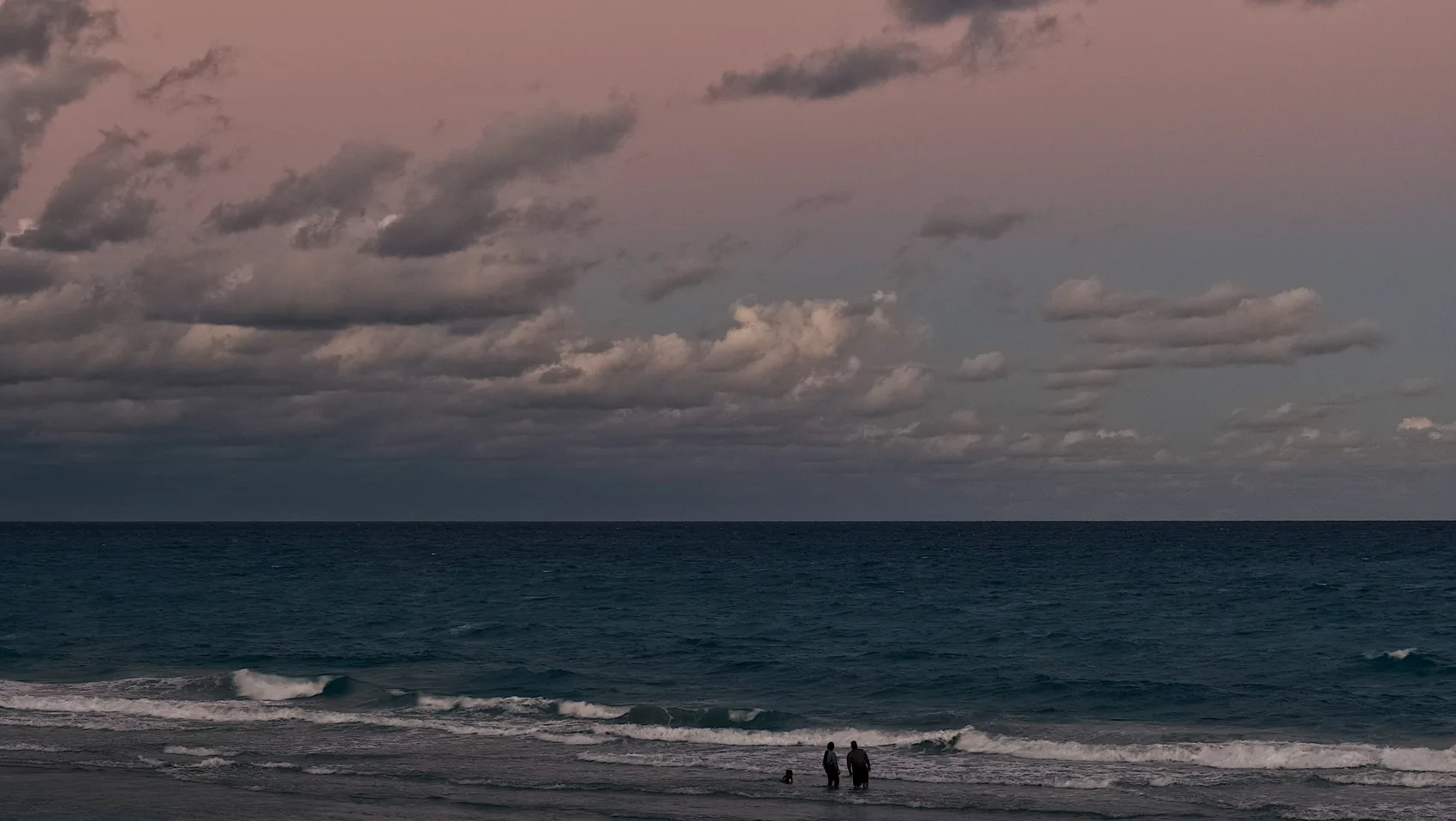 Pink clouds over a dark Jupiter ocean horizon.