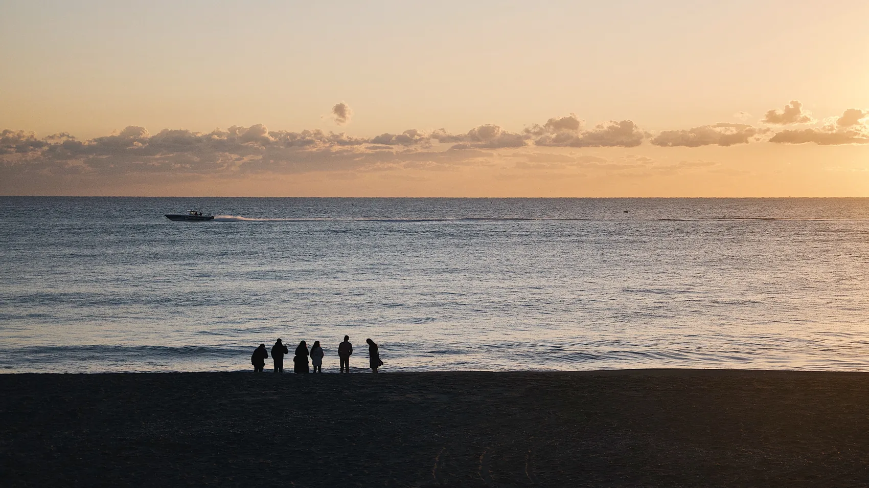 Small figures on a Jupiter beach at sunset.