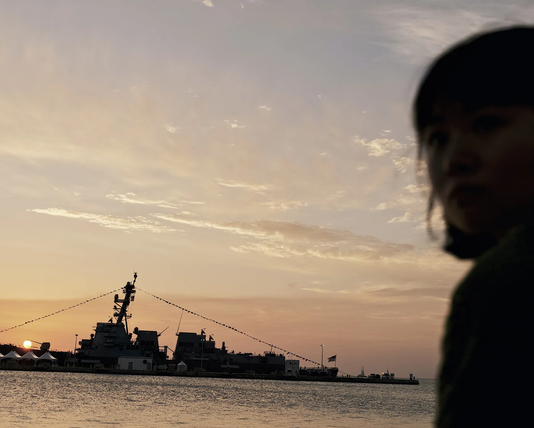 A silhouetted figure beside Key West harbour at dusk.