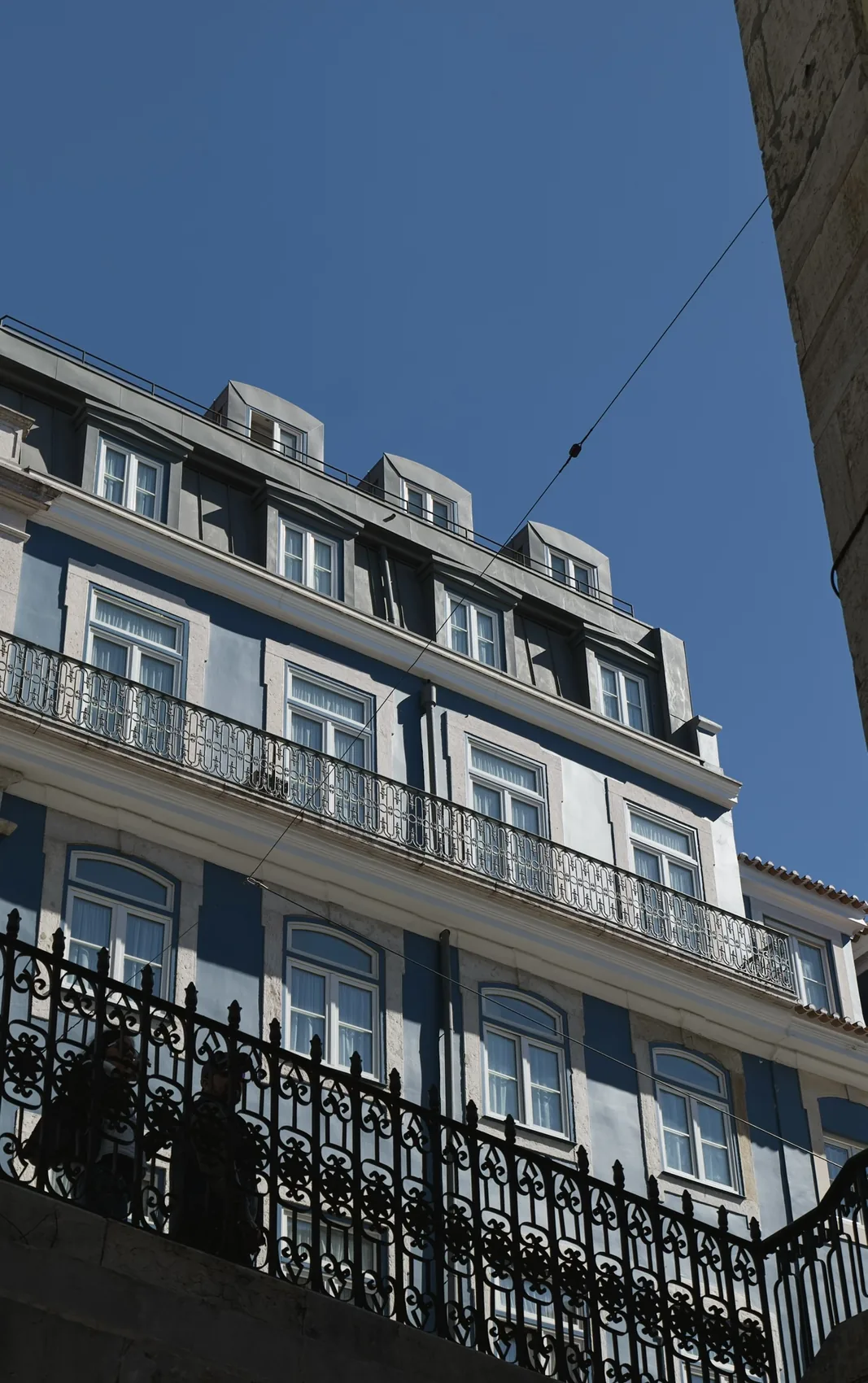A blue Lisbon facade rising into hard sun.