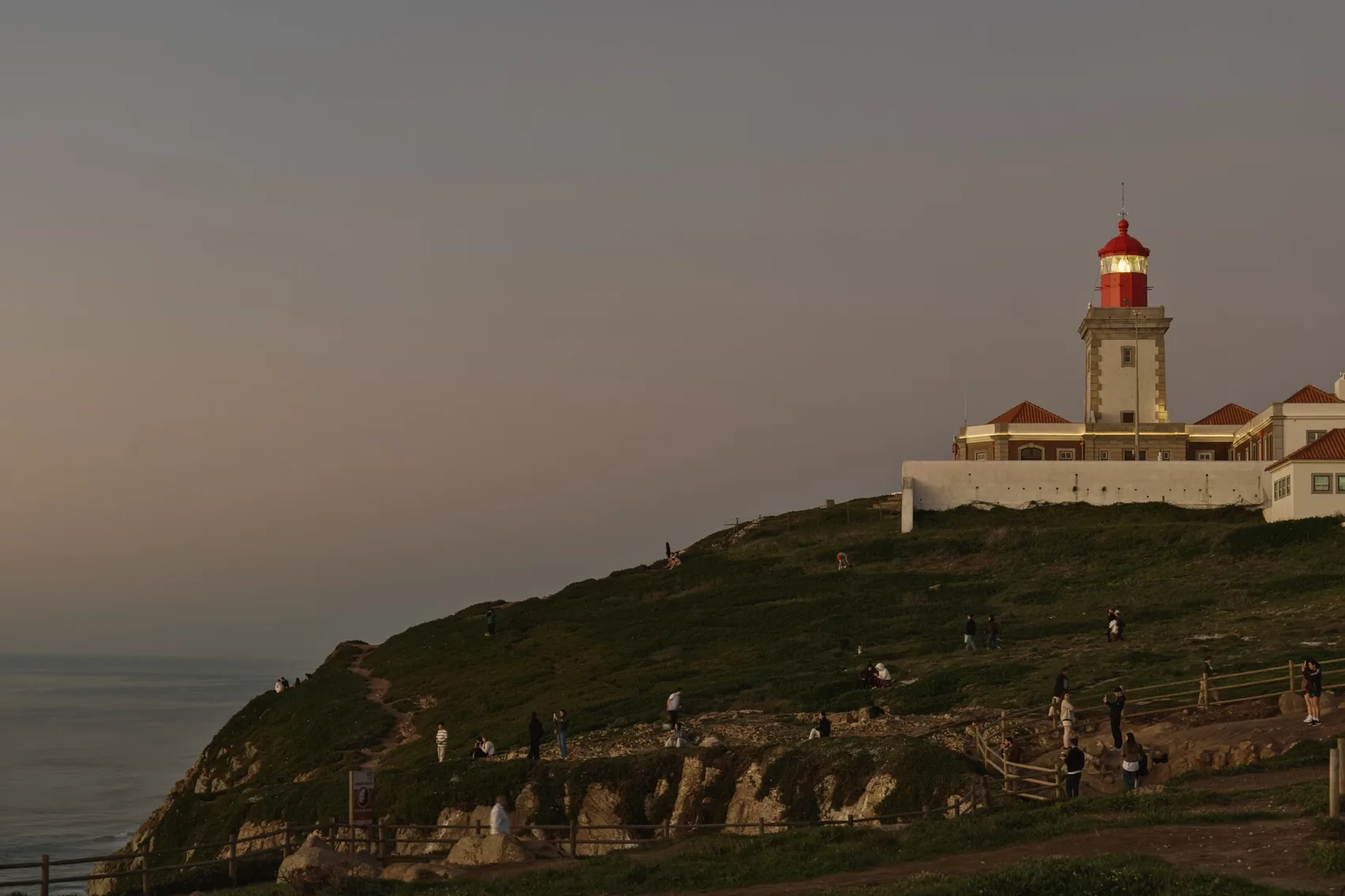 A lighthouse on a cliff near Lisbon at dusk.