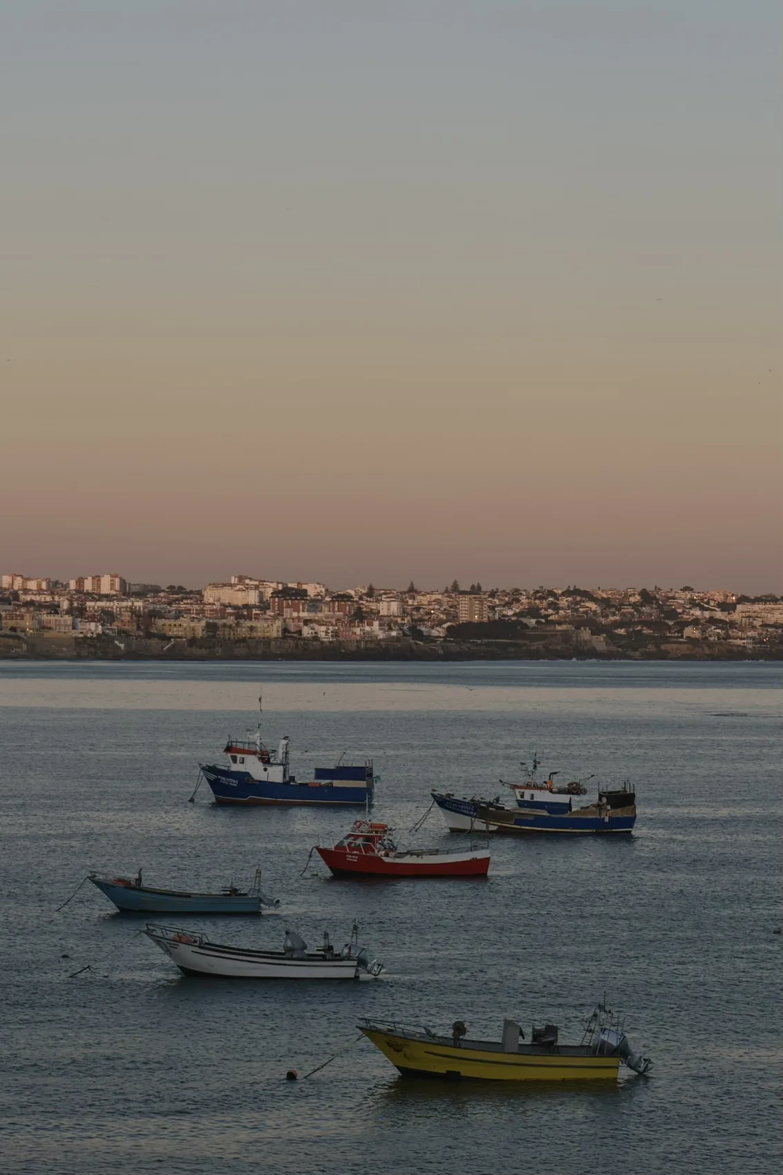 Small boats on the Lisbon river at dusk.