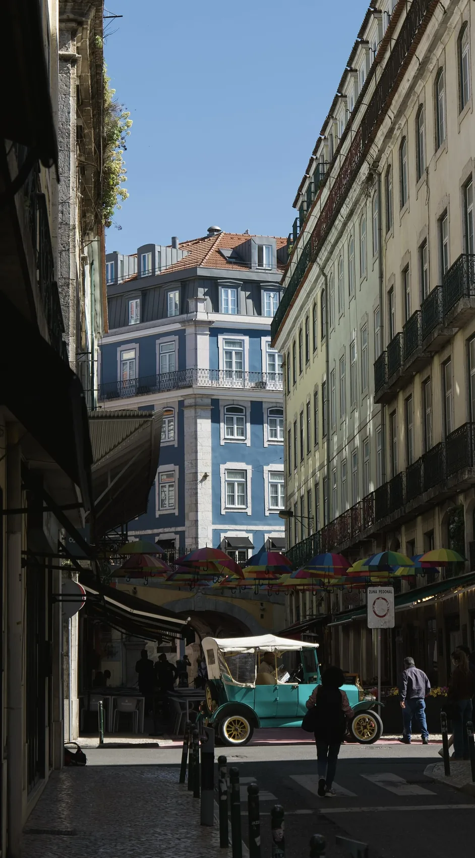 A Lisbon street opening to a small tram and bright buildings.