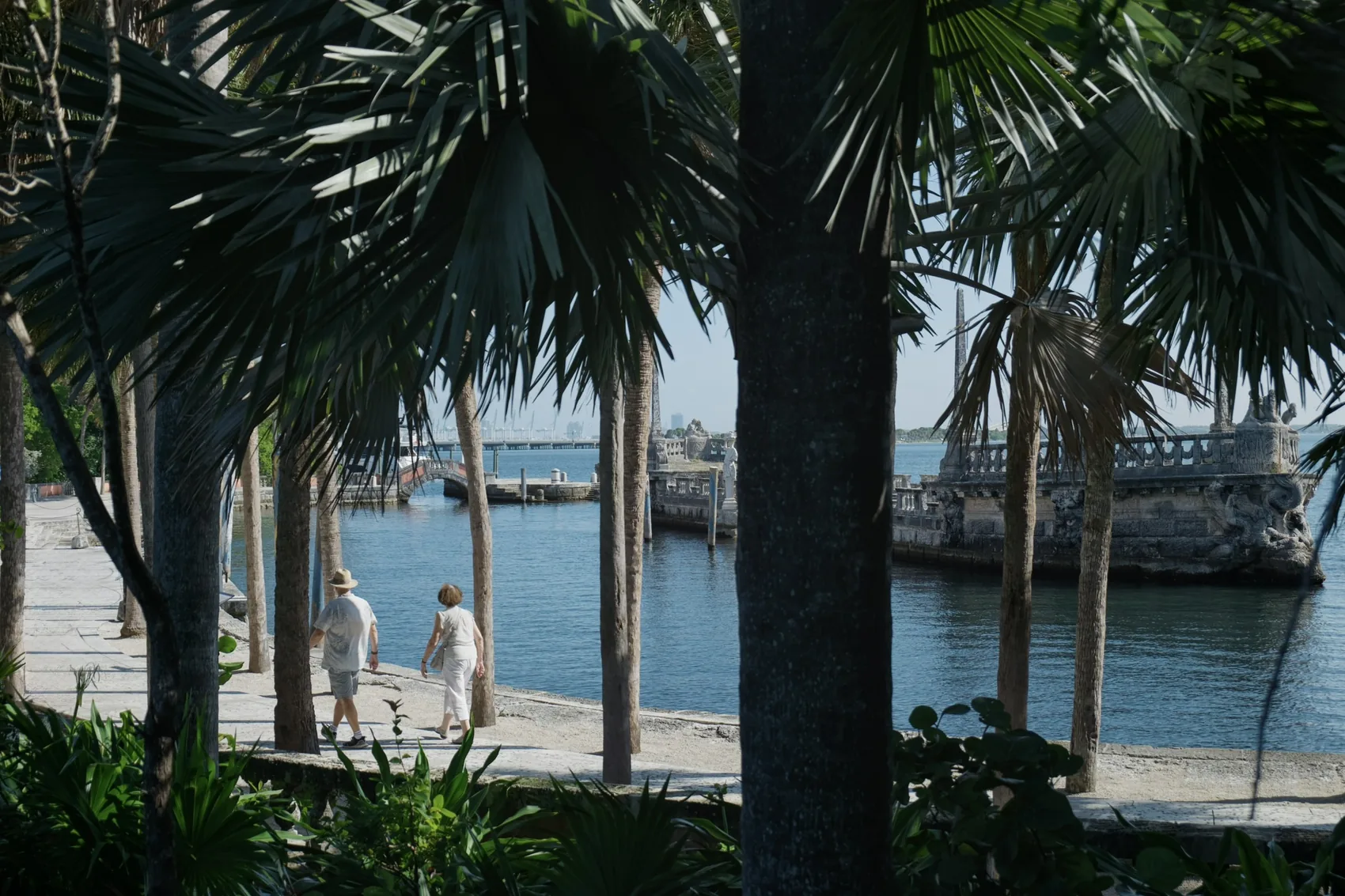 Palms framing blue water and statues in Miami.