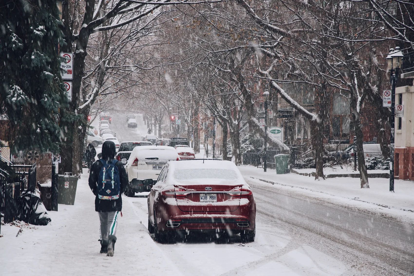 A red car and pedestrian on a snowy Montreal street.