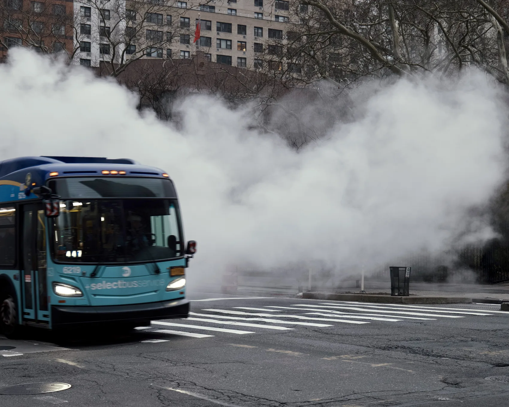 A New York bus emerging through street steam.