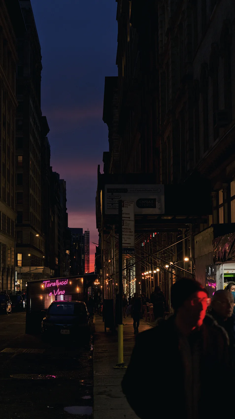 A dark New York street with a small red-lit figure.