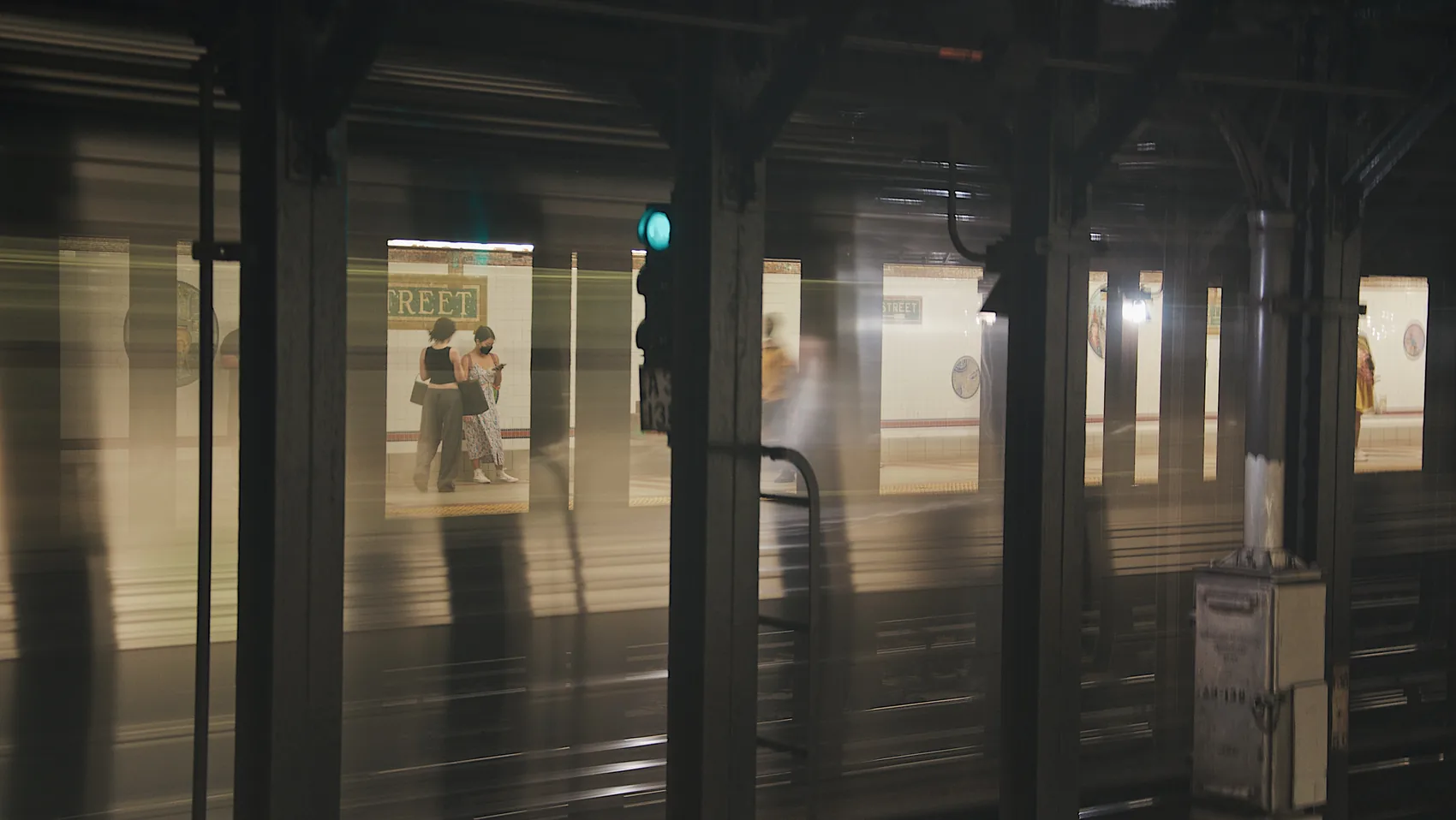 A New York subway platform viewed through pillars.