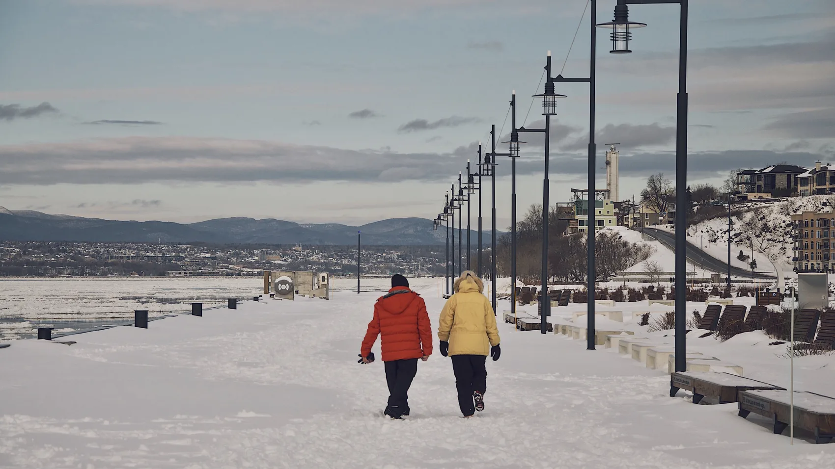Two people walking along a snowy Quebec City promenade.
