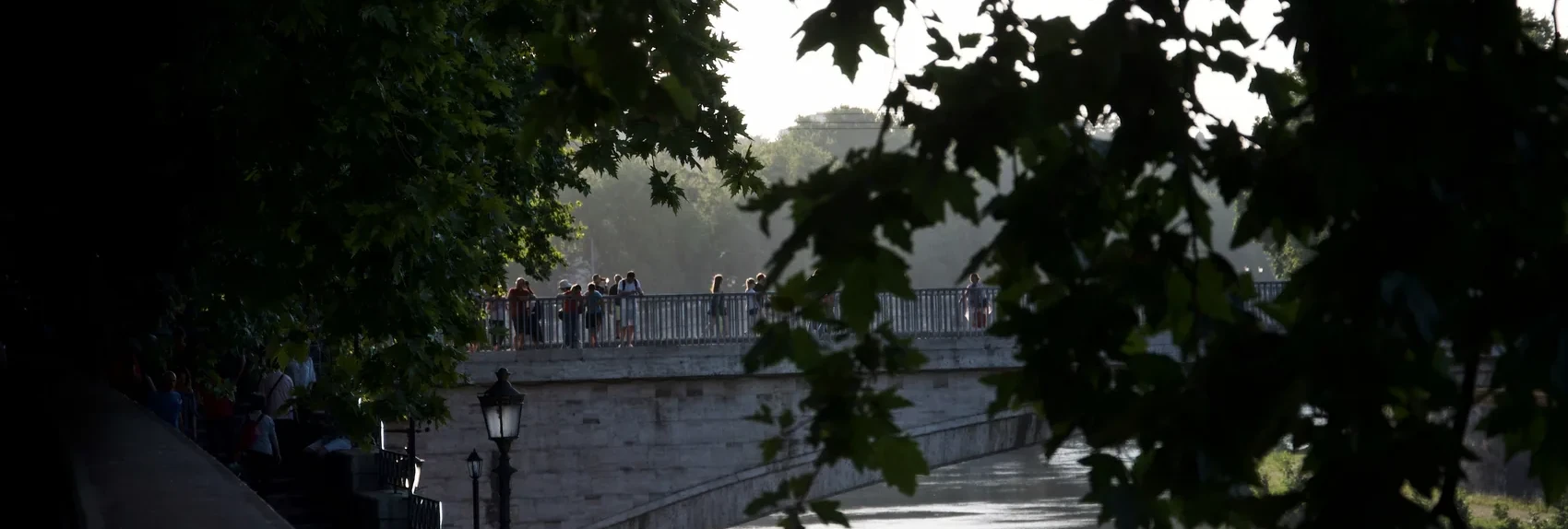 The Tiber seen through dark Rome leaves.