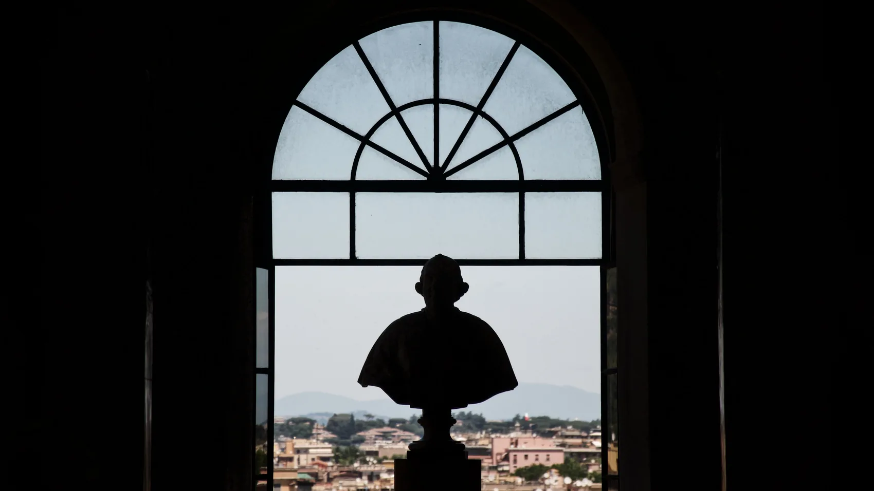 A bust silhouetted in a Rome window opening.