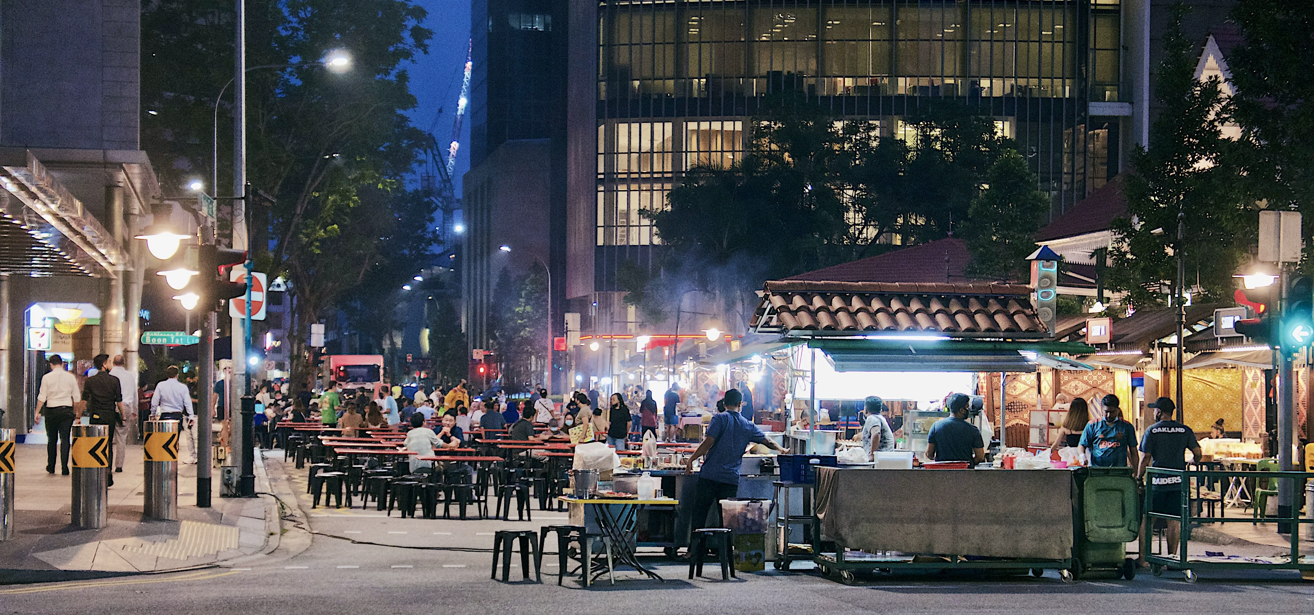 Hawker stalls and diners on a Singapore street at night.