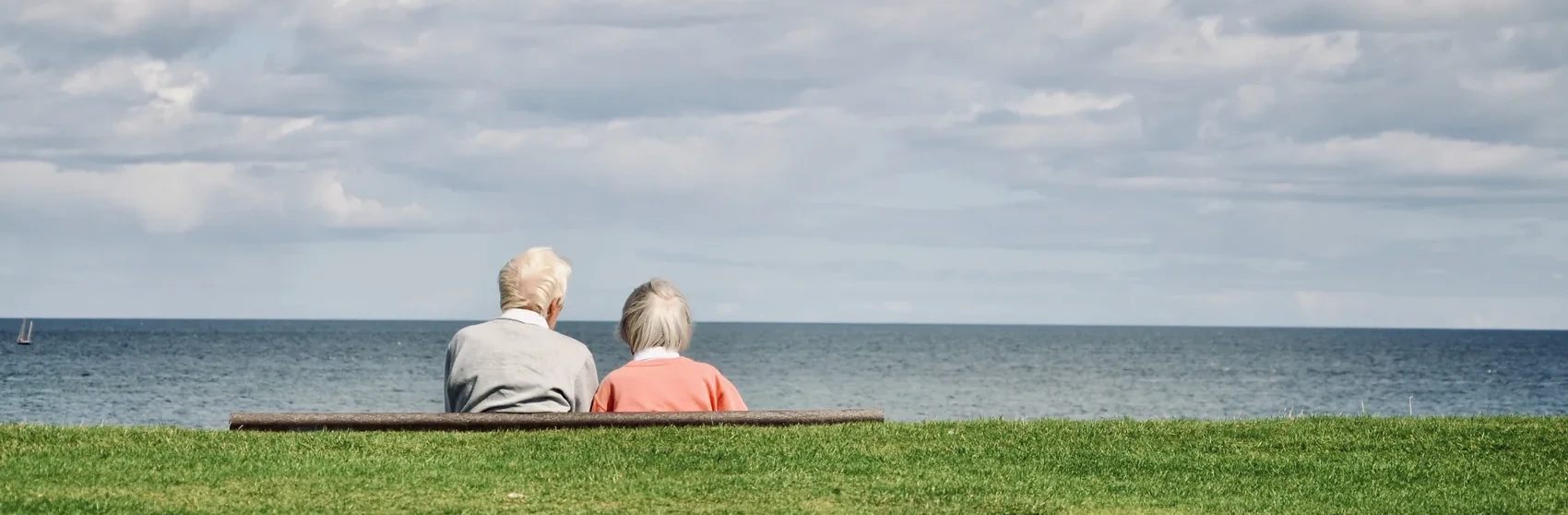 Two people sitting on a bench facing the sea at St Andrews.