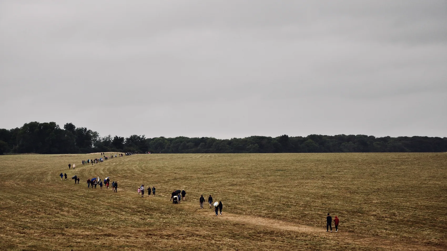 Visitors crossing the open field near Stonehenge.