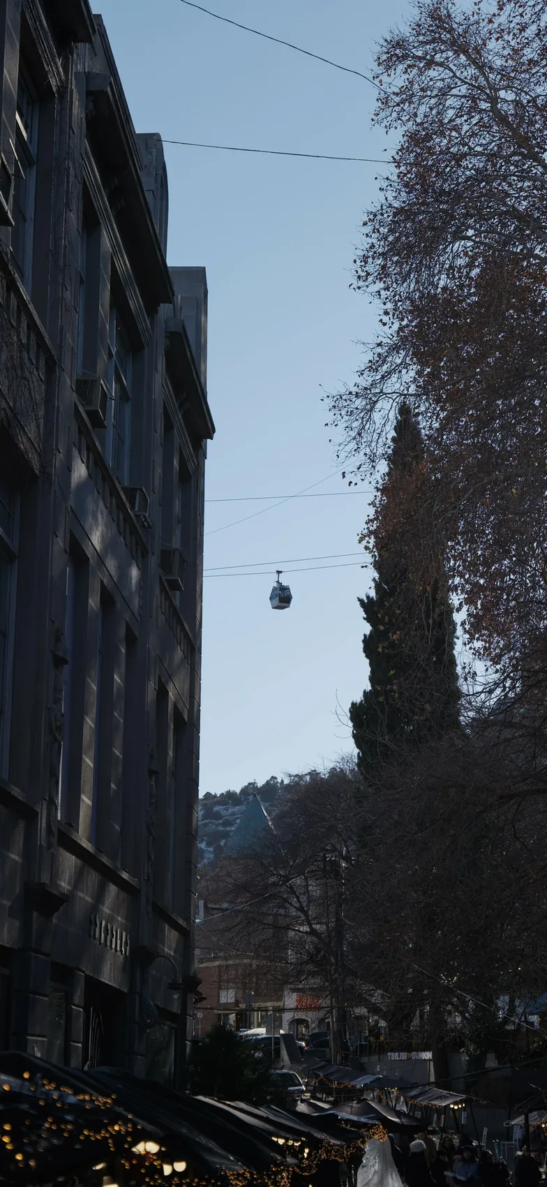 A narrow Tbilisi street with a cable car overhead.