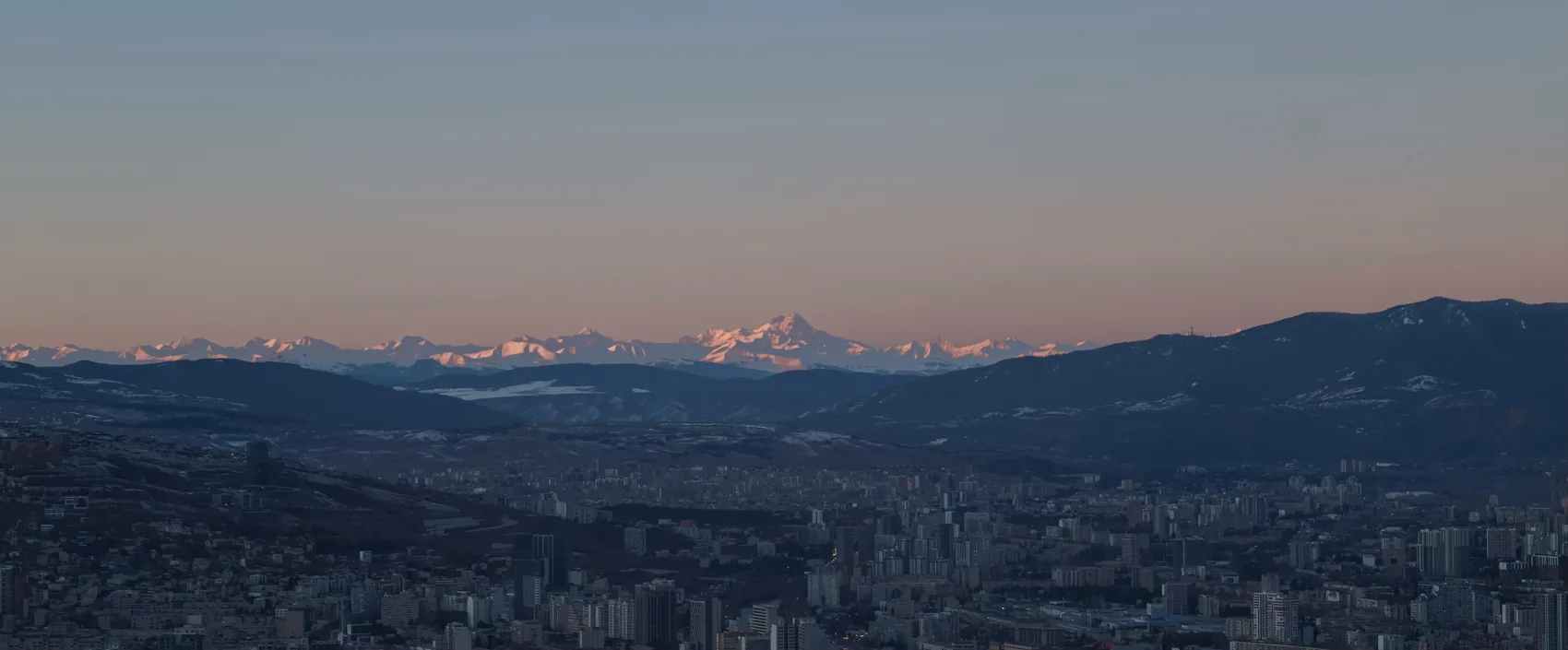 A wide view over Tbilisi toward snowy mountains.