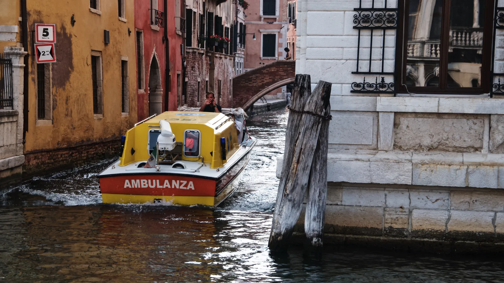 A yellow ambulance boat on a Venice canal.