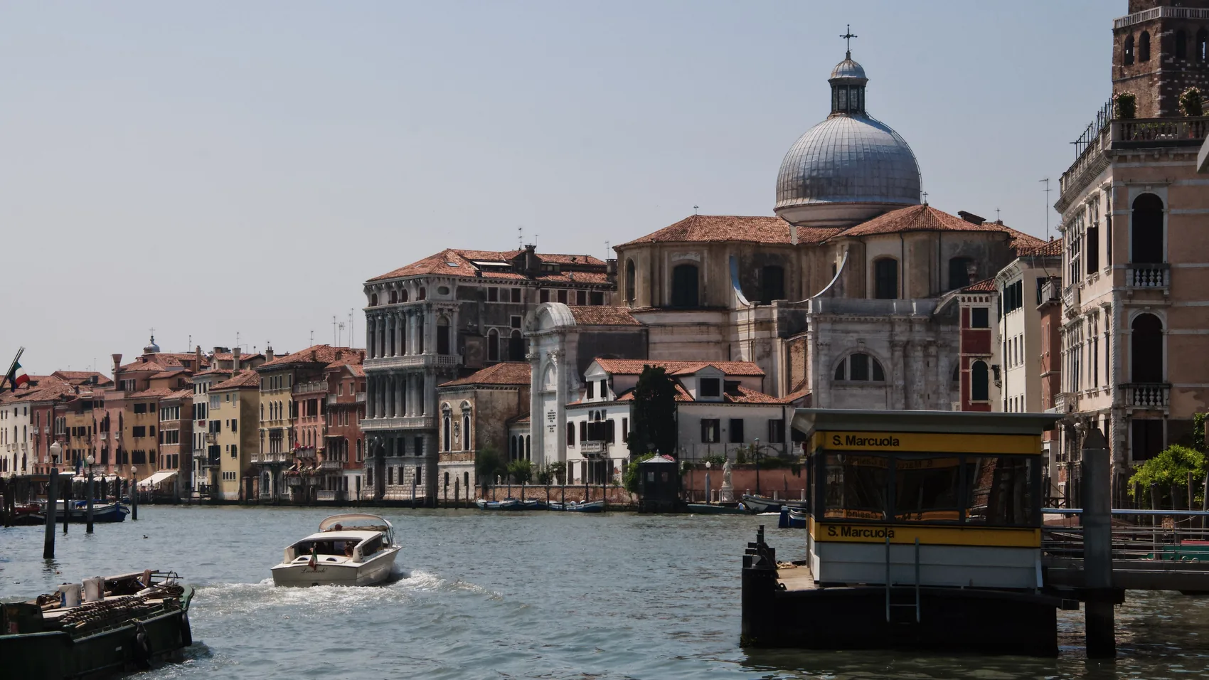 A Venice canal entrance with boats and domes.