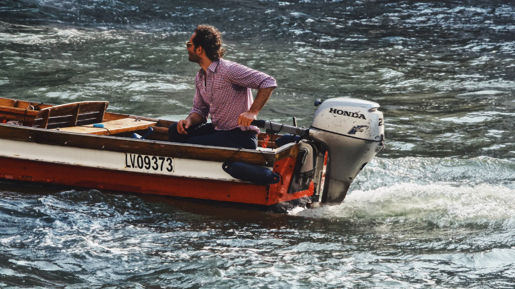 A motorboat cutting through bright Venice water.