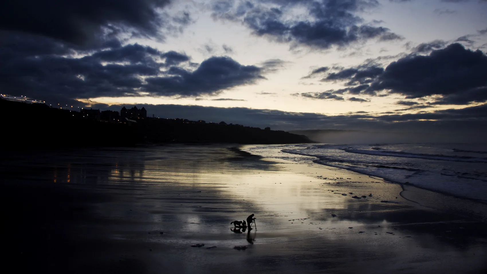 A dark reflective beach under evening clouds in Whitby.